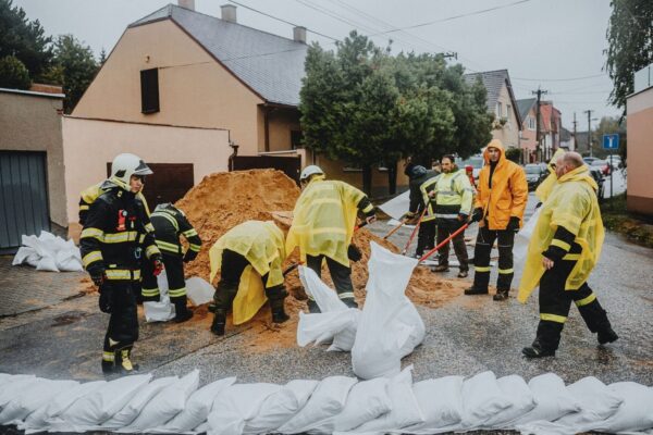 Firefighters and volunteers fill sandbags on a rainy residential street